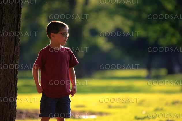 Little boy standing in park in summer.