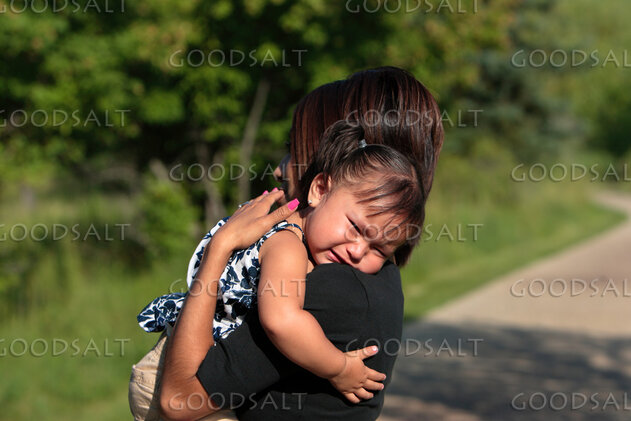 Woman comforting crying little girl outdoors.