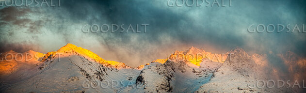 Bright morning sun on side of mountains with low cloud.