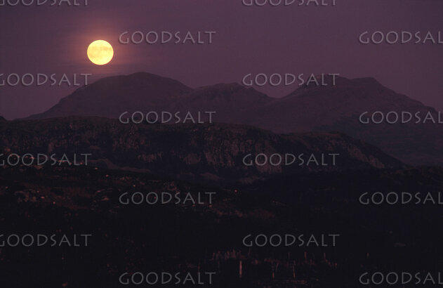 The bright moon shining over dark mountains.