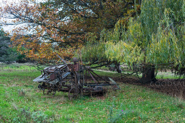 Vintage machinery in the yard of an abandoned farmhouse.