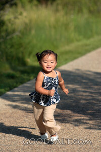 Happy little girl running on sidewalk.