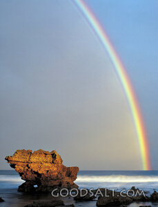large rock at the ocean with rainbow