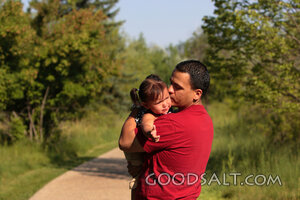 Man comforting crying little girl outdoors.
