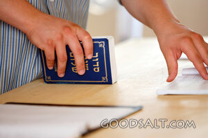 Man’s hands holding Hebrew prayer book.