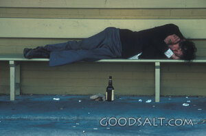 Homeless Man Sleeping Beside a Bottle