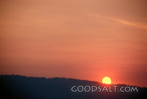 A bright red sunset over a dark mountain.