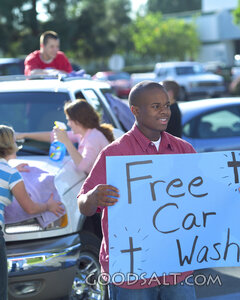 Teenagers washing cars while another boy holds up a "Free Car Wash" sign.