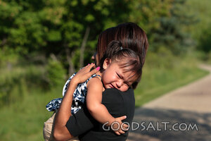 Woman comforting crying little girl outdoors.