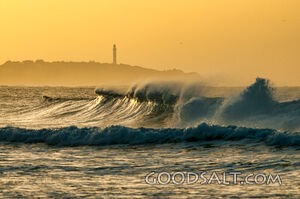 Distant lighthouse in hazy background with large waves.