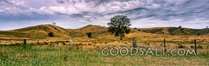 Farm hills and infrastructure in green hilly land with dramatic sky.