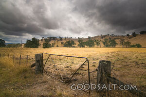 Farm hills and infrastructure in green hilly land with dramatic sky.