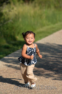 Happy little girl running on sidewalk.