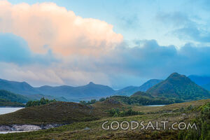 Hills and sunset sky around lake.