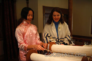 IDAHO. Boise. Asian Jewish girl reading Torah scroll using a