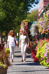 IDAHO. Boise. Two women walking past hanging flower baskets 