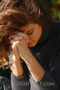 IDAHO. Boise. Young woman praying with face hidden (close-up