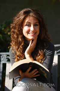 IDAHO. Boise. Young woman reading Bible outdoors and smiling