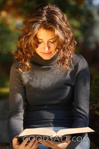 IDAHO. Boise. Young woman reading Bible outdoors (close-up).
