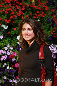 IDAHO. Boise. Young woman smiling near hanging flower basket