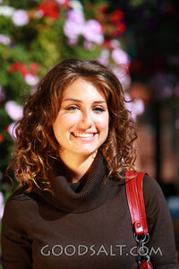 IDAHO. Boise. Young woman smiling near hanging flower basket
