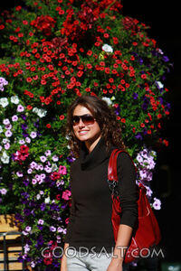 IDAHO. Boise. Young woman smiling near hanging flower basket