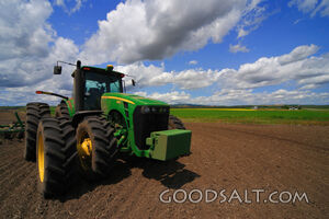 John Deere 8430 farm tractor with fields and clouds behind.