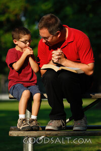Man and little boy praying outdoors in summer.