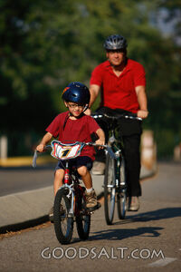 Man and little boy riding bicycles outdoors in summer.