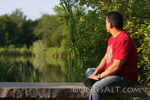 Man gazing across pond in summer.