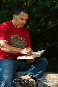 Man reading book outdoors in summer.