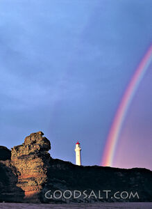 rock formation with rainbow and lighthouse
