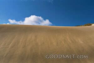 sand dune with blue sky and fluffy clouds