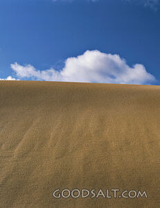 sand dune with blue sky and fluffy clouds
