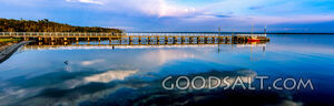 Small jetty and boat on huge still lake in early morning.