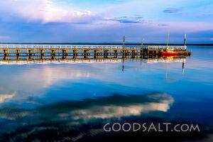 Small jetty and boat on huge still lake in early morning.