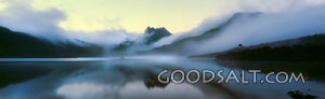 Still reflective lake with heavy pink fog at sunrise.
