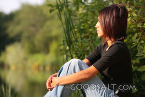 Woman gazing across pond in summer.